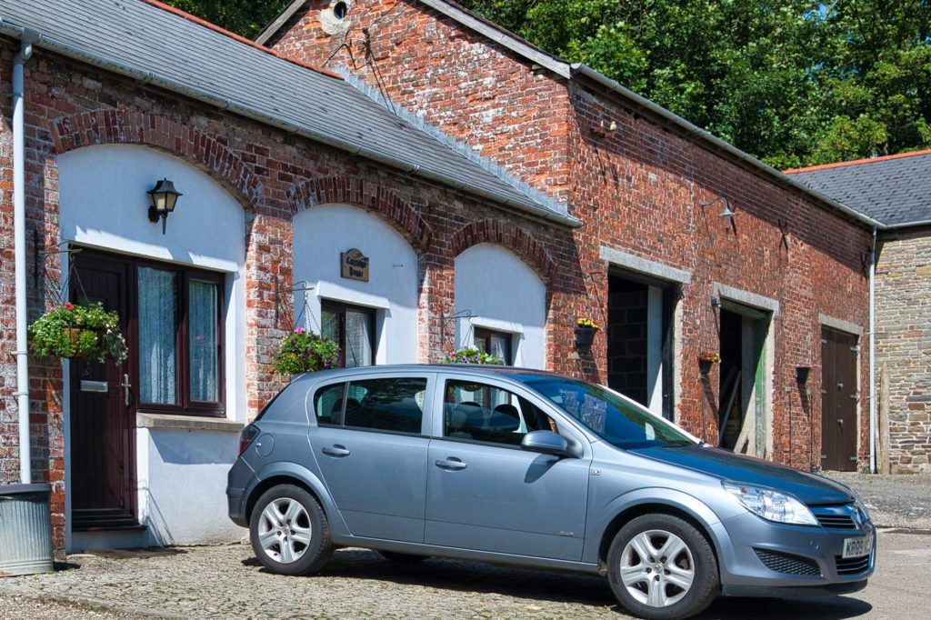 Silver car parked outside red brick converted stable building