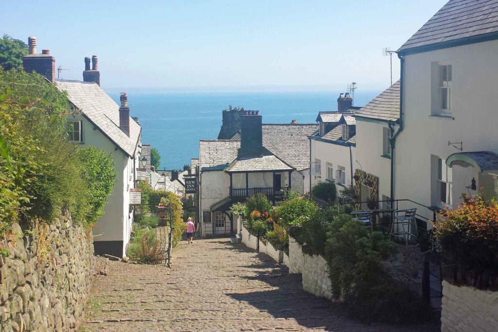 view down cobbled street with cottages and sea view