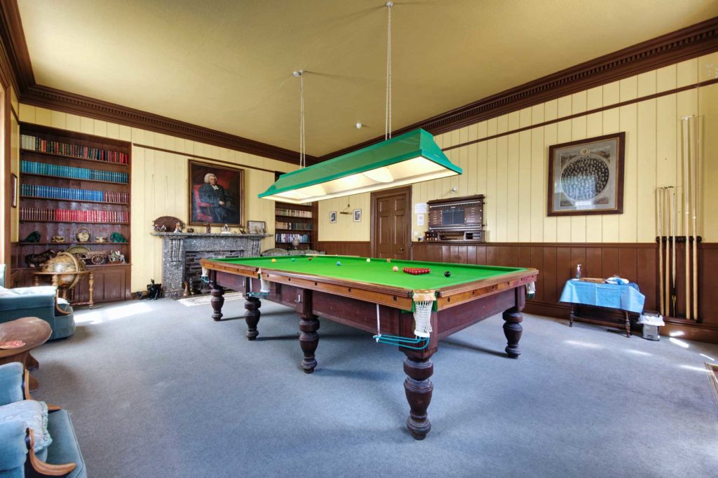 Snooker room with bookcase and period portrait on wall