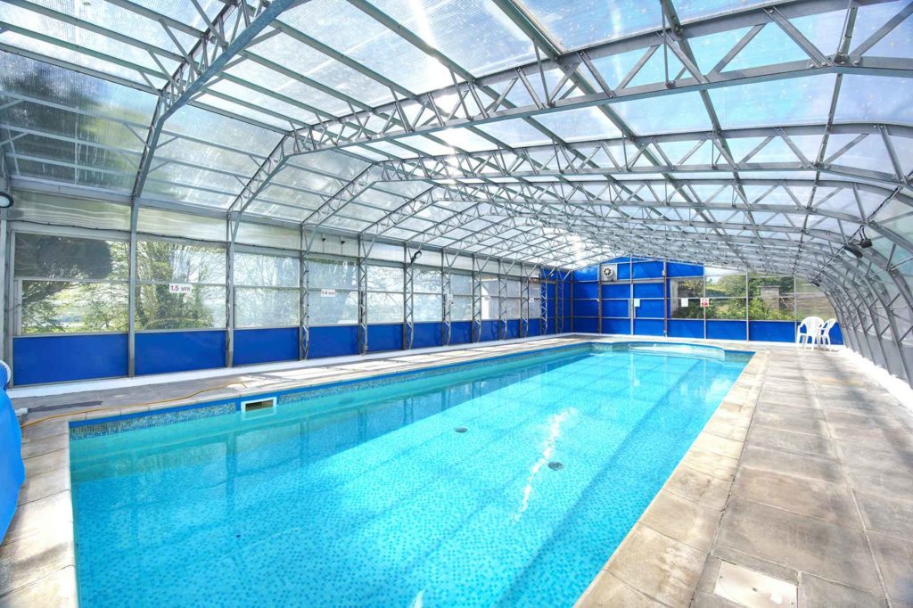 Bright aqua swimming pool with metal and glass ceiling