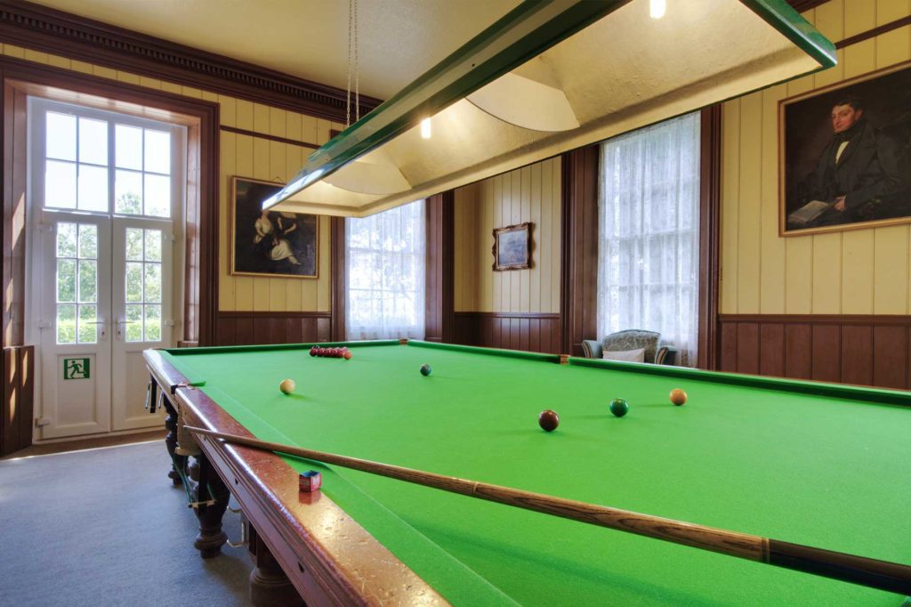 Snooker table in room with french doors and period portrait paintings